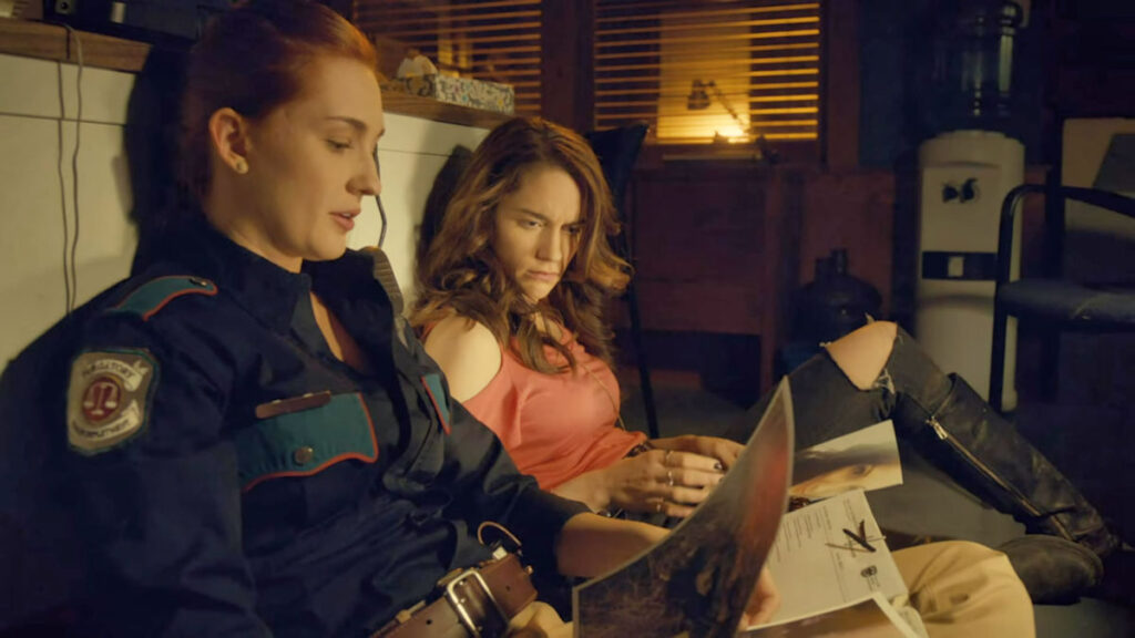 Haught (Kat Barrell) and Wynonna (Melanie Scrofano) with whiskey and autopsy photos - Wynonna Earp 107