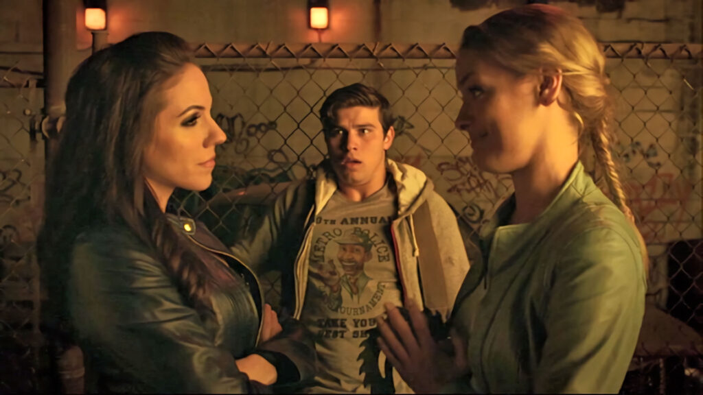Bo (Anna Silk) and Tamsin (Rachel Skarsten) argue over what to do with Mark (Luke Bilyk), who is wearing an interesting t-shirt borrowed from Bo. - Lost Girl 504