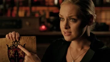 Tamsin (Rachel Skarsten) points to the Queen Bee in the Crest of Raina